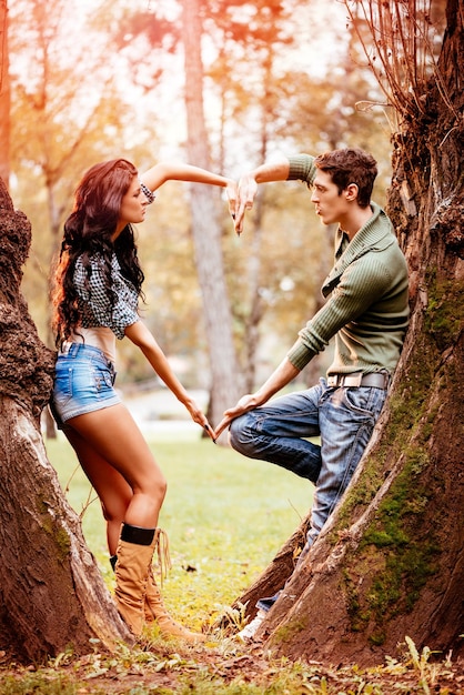 Foto bella coppia adorabile che si gode nel parco soleggiato nei colori autunnali e con le mani a forma di cuore.