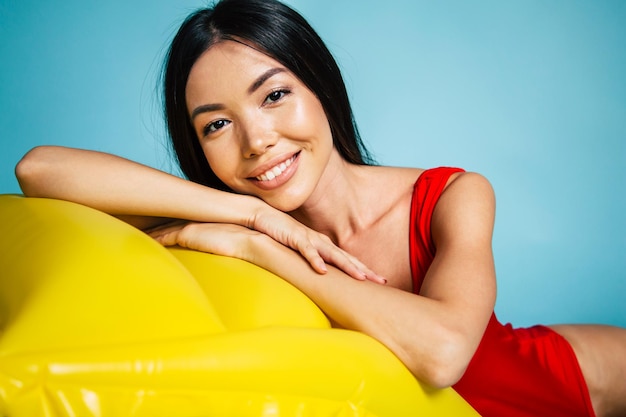 Beautiful lovely Sexy asian woman standing on blue background in swimsuit or bikini and smiling while posing. Summertime and vacation