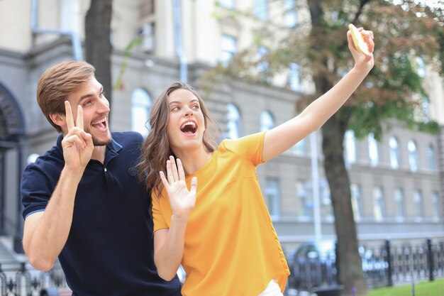 Beautiful lovely young couple walking at the city streets, taking a selfie.