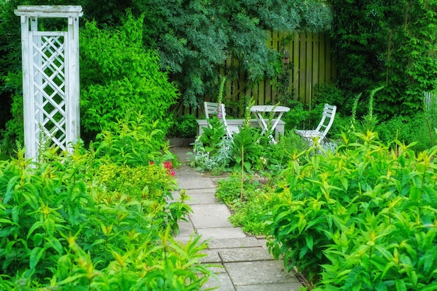 A beautiful lush green garden with a table and chairs in a backyard on a summers day Vibrant park with scenic views of nature in a peaceful tranquil spot Venue for a zen picnic or lunch date