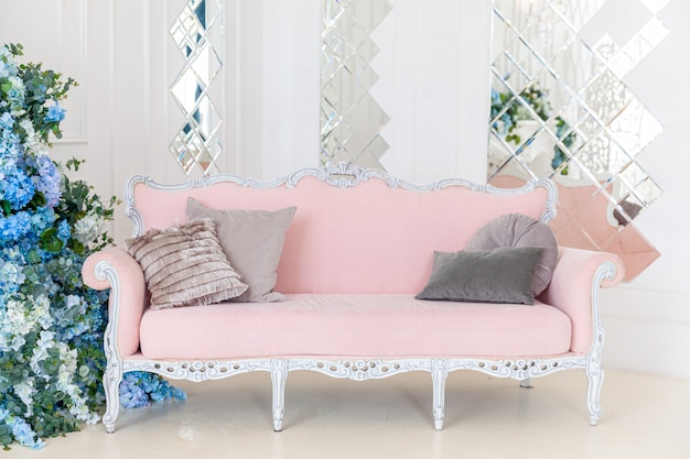 Beautiful luxury classic clean interior living room in white color with pink sofa flower composition. Bright modern stylish interior living room with furniture in classic minimalist style.