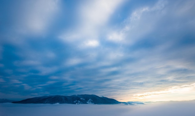 산봉우리의 아름다운 마법의 전망은 일몰에 대한 따뜻한 가을 저녁에 안개와 권운 사이에 있습니다. 자연 현상과 세계의 불가사의의 개념