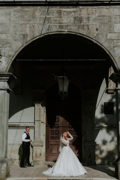 Beautiful magical young bride holding hands handsome groom under castle arc