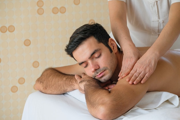 Beautiful man during massage with essential oil in room spa