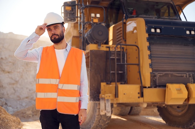 Foto bell'uomo in uniforme sta lavorando nella cava durante il giorno con il camion di trasporto