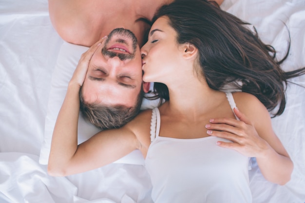 Beautiful man and woman are lying in white bed