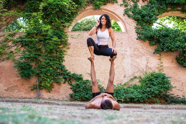 Beautiful man and woman doing acroyoga in the garden or park Harmony and relaxation