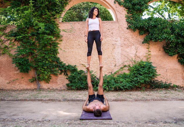 Beautiful man and woman doing acroyoga in the garden or park Harmony and relaxation