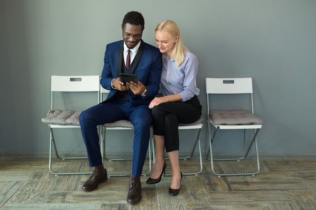 Photo beautiful man and woman in the office on chairs