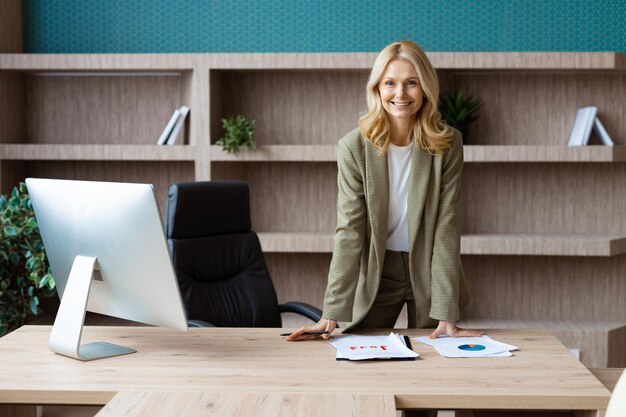 Foto bella donna d'affari adulta matura con abito elegante seduto alla scrivania del computer in ufficio