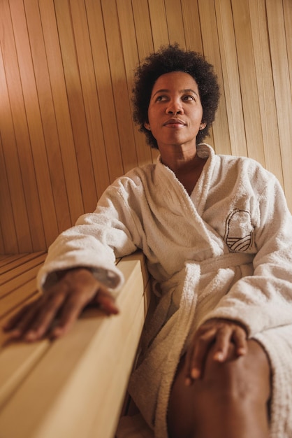 Beautiful mature African American woman relaxing in a sauna at the spa centre.