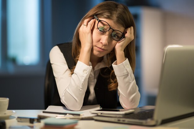 Beautiful mature business woman workaholic tired working in the\
office until the night on overtime