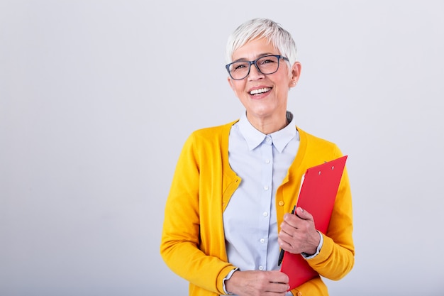 Foto bella scrittura matura della donna di affari in lavagna per appunti isolata sul rosa. donne sorridenti di affari del ritratto con la lavagna per appunti e documento in mani