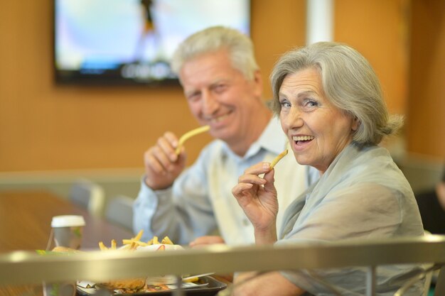 Bella coppia matura che mangia patatine fritte al caffè?