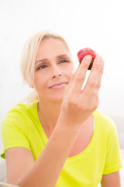 A beautiful mature woman eating strawberry at home.
