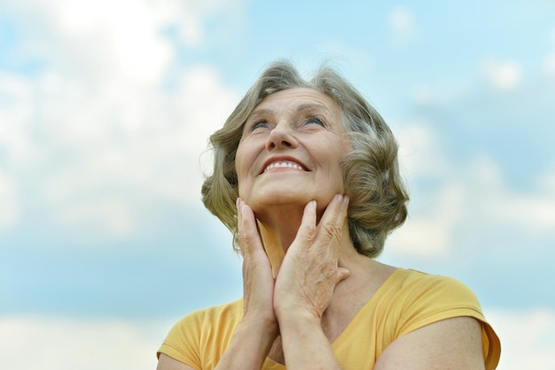 Beautiful mature woman, posing against blue sky with clouds