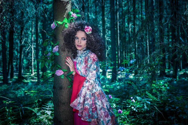 Foto bella donna adulta che indossa abiti tradizionali mentre è in piedi nella foresta