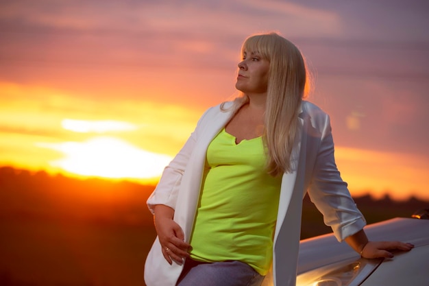 Beautiful middle age blond woman against sunset sky