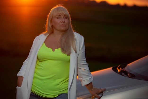 Beautiful middle age blond woman against sunset sky