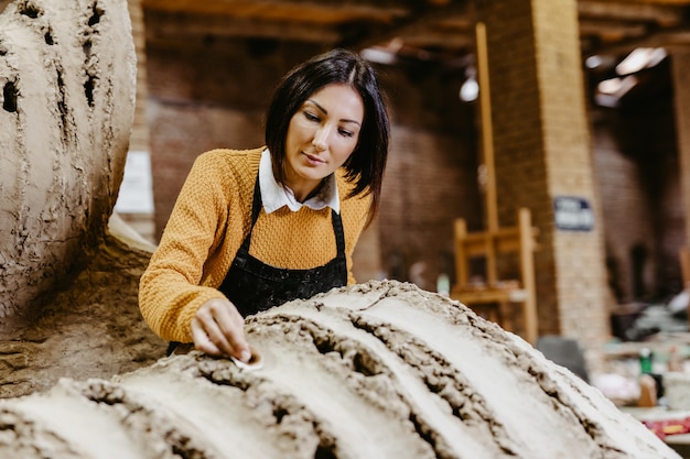 Beautiful middle age woman professional sculptor working on gorgeous sculpture.