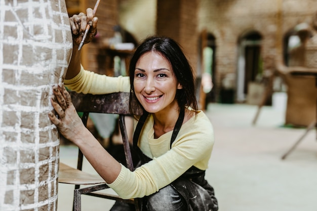 Beautiful middle age woman professional sculptor working on gorgeous sculpture.