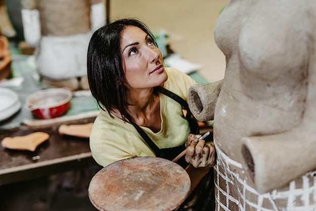 Foto scultore professionista di bella donna di mezza età che lavora su una splendida scultura.