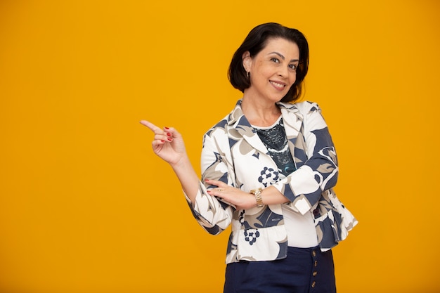 Beautiful middle-aged business woman smiling and pointing