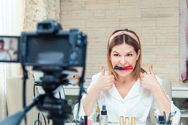 Блогер красивая женщина средних лет показывает, как пользоваться косметикой. Запись живого видео в блоге дома. Современный вариант работы в домашних условиях.