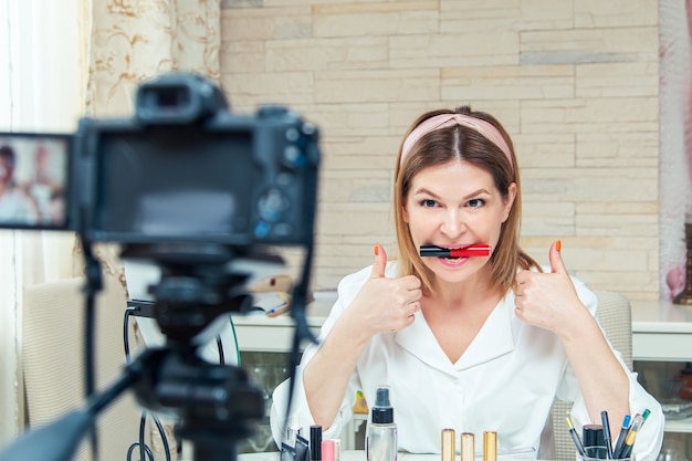 Beautiful middle aged woman blogger shows how to use cosmetics. Live video blog recording at home. The modern version of the work at home.