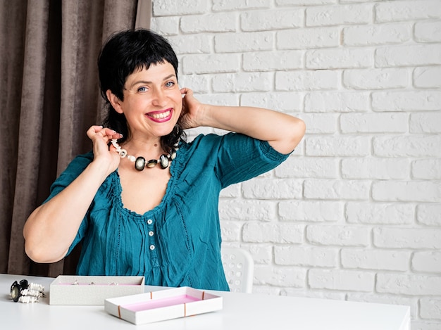 Beautiful middle aged woman trying on the jewelery