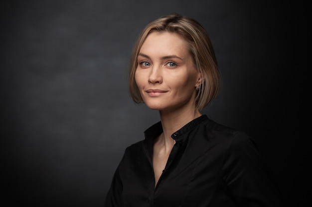 Beautiful middleaged woman on a gray background in a black blouse