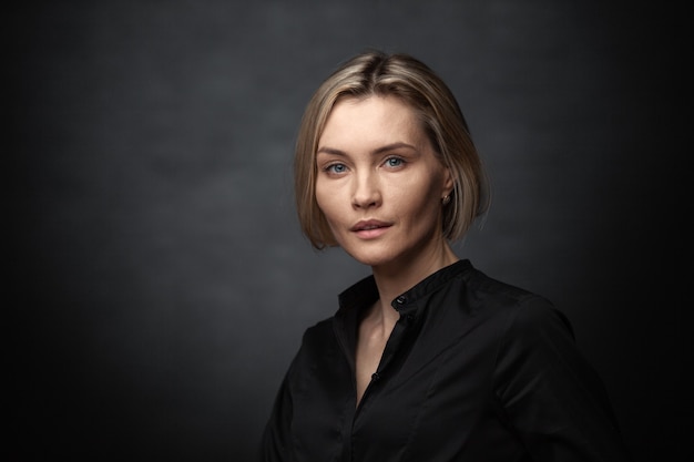 Beautiful middleaged woman on a gray background in a black blouse