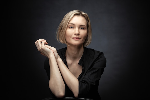 Beautiful middleaged woman on a gray background in a black blouse