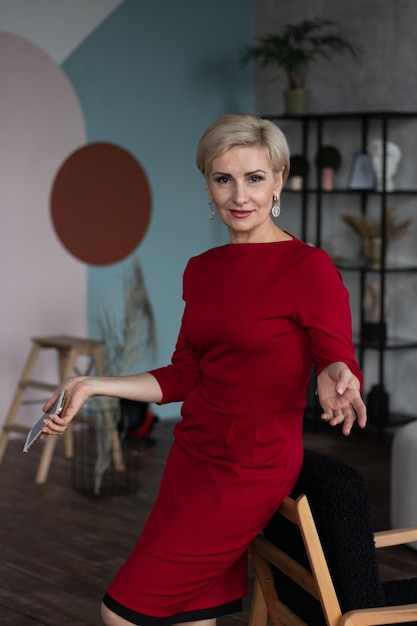 Beautiful middleaged woman in red dress sitting on a chair with cellphone