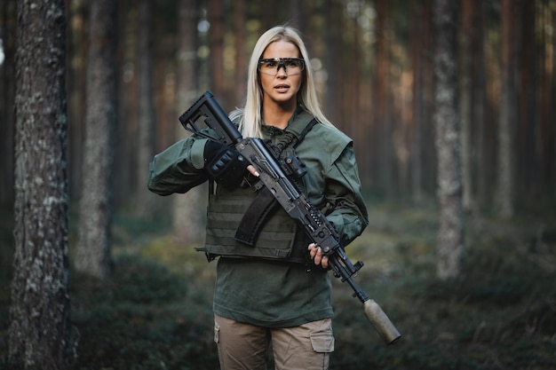 Foto bella ragazza militare con un moderno fucile ak-12 nella foresta in guerra