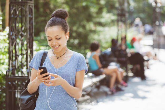 Beautiful Mixed-Race Young Woman Listening Music With Earphones at Park