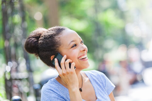 携帯電話で話している美しい混血の若い女性