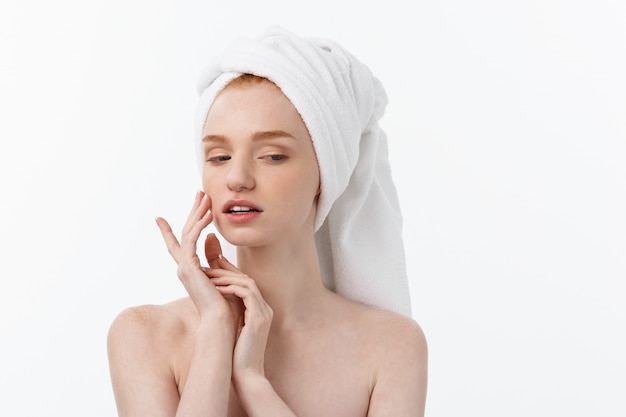 Bellissima modella applicando il trattamento cosmetico in crema sul viso su bianco.