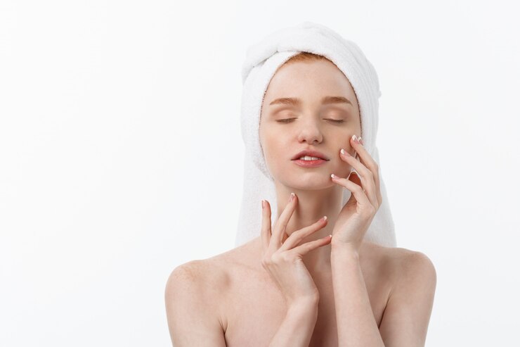 Photo beautiful model applying cosmetic cream treatment on her face on white.