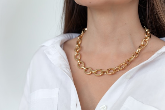 Beautiful model brunette in modern gold metal necklace chain