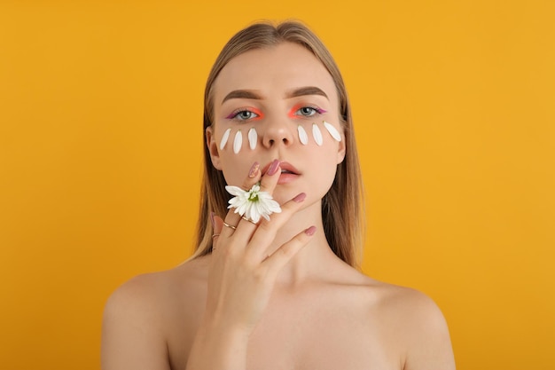 Beautiful model girl with flower on yellow background