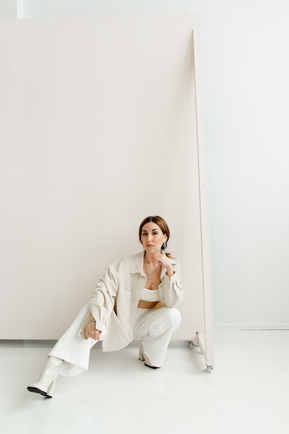 사진 스튜디오에서 사진 촬영을 위해 흰 옷을 입은 아름다운 모델