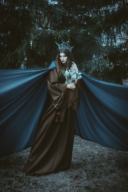 Foto il bello modello sta posando in una foresta con tessuto blu
