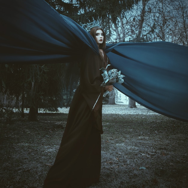 Beautiful model is posing in a forest with blue fabric