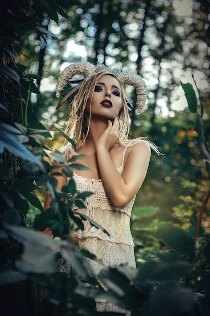 Beautiful model is posing in a forest with white horns