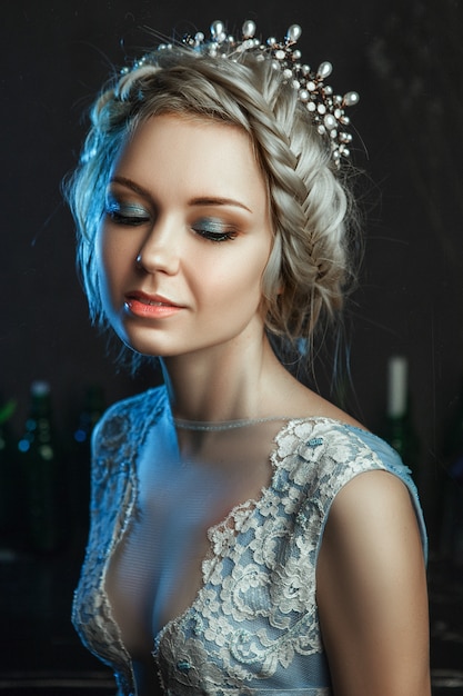 Beautiful model wearing light blue dress is posing in a studio