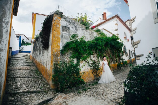 Beautiful model wearing white dress  is posing next to an old castle