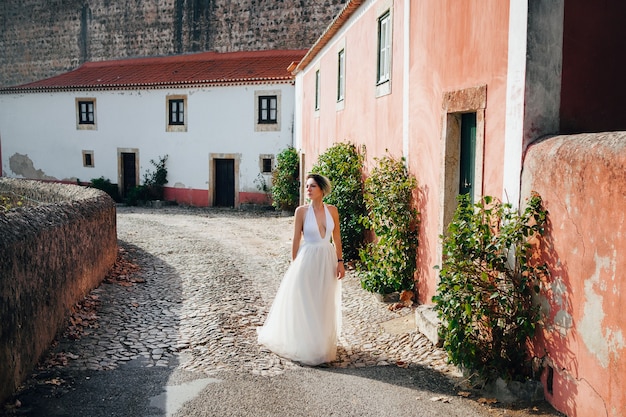 Beautiful model wearing white dress  is posing next to an old castle