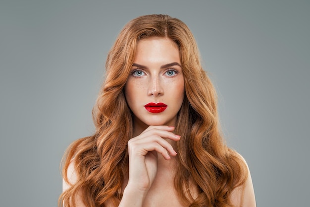 Beautiful model with long curly red hair looking at camera. Wavy shiny hair, perfect face