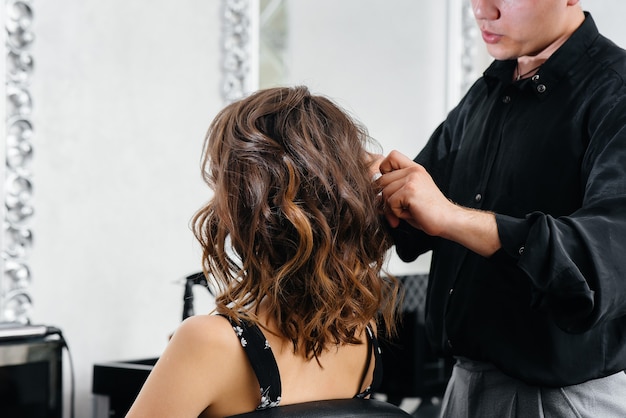 In a beautiful, modern beauty salon, a professional stylist makes a haircut and hairstyle for a young girl. Beauty, and fashion.